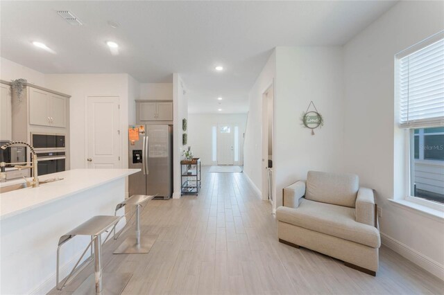 kitchen featuring light countertops, a sink, a breakfast bar, light wood-type flooring, and stainless steel appliances
