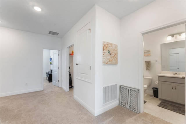 hallway with light carpet, baseboards, and visible vents