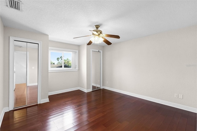 7706 Waunatta Ct, Winter Park, FL 32792 - unfurnished bedroom with multiple closets, a textured ceiling, visible vents, baseboards, and dark wood-style floors