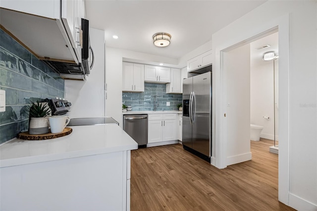 5980 32nd Ave N, Saint Petersburg, FL 33710 - kitchen with stainless steel appliances, backsplash, white cabinetry, wood finished floors, and recessed lighting