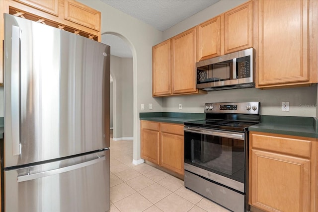 529 Tuten Trl, Orlando, FL 32828 - kitchen with arched walkways, a textured ceiling, light tile patterned flooring, dark countertops, and stainless steel appliances