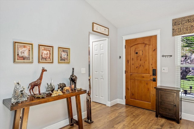 foyer entrance with vaulted ceiling, wood finished floors, and baseboards