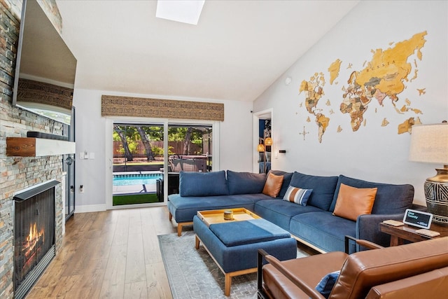 living area with a brick fireplace, hardwood / wood-style floors, and vaulted ceiling