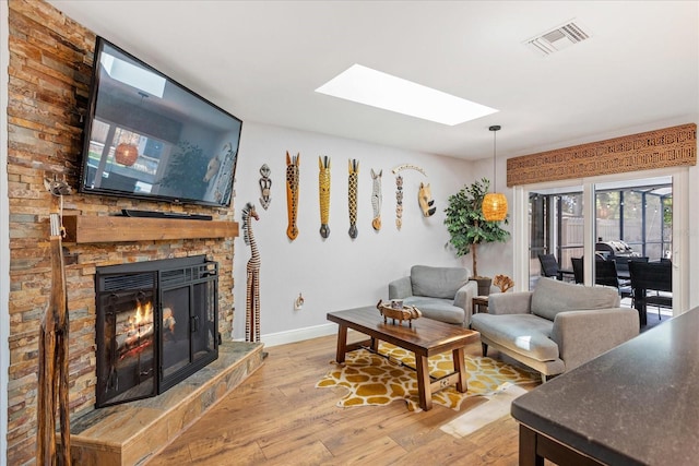 living area with light wood-style floors, baseboards, a skylight, and a fireplace
