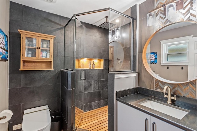 full bathroom featuring a tile shower, toilet, and vanity