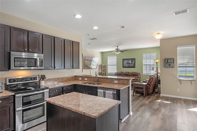 kitchen featuring light wood-style flooring, visible vents, a kitchen island, a sink, and stainless steel appliances