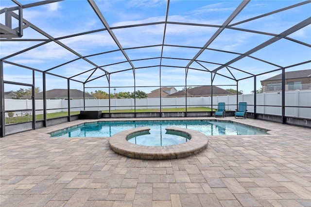 view of pool with a fenced backyard, a pool with connected hot tub, a patio, and glass enclosure