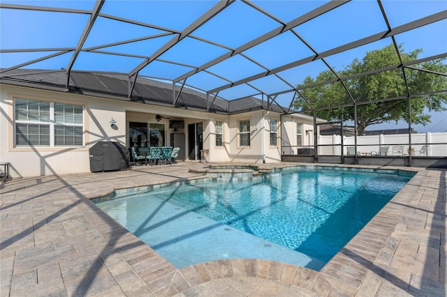 view of swimming pool with a pool with connected hot tub, a grill, a ceiling fan, glass enclosure, and a patio area
