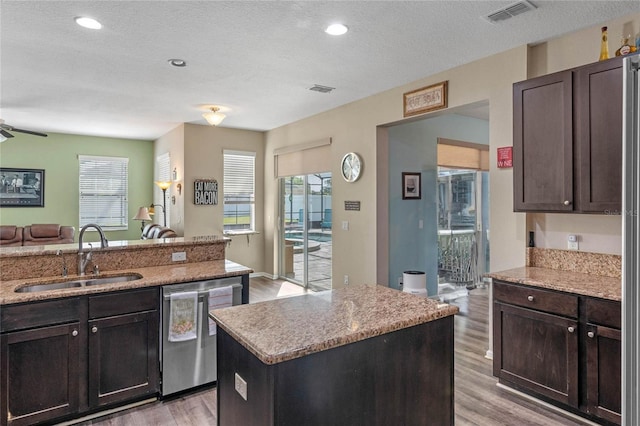 kitchen featuring open floor plan, light wood-style flooring, visible vents, stainless steel dishwasher, and a sink