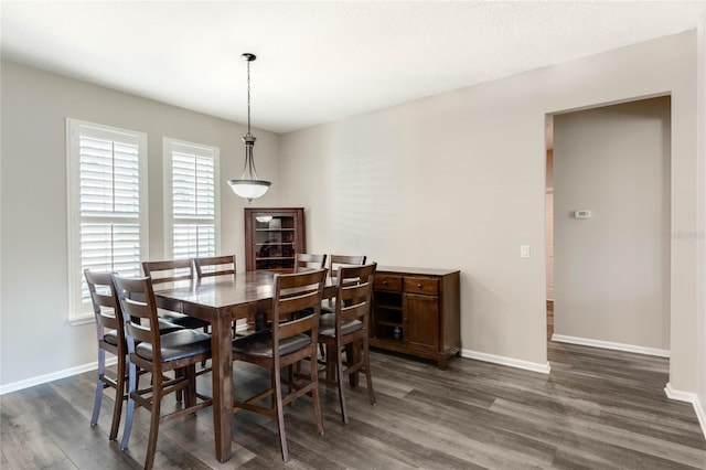 dining space featuring baseboards and dark wood-style floors