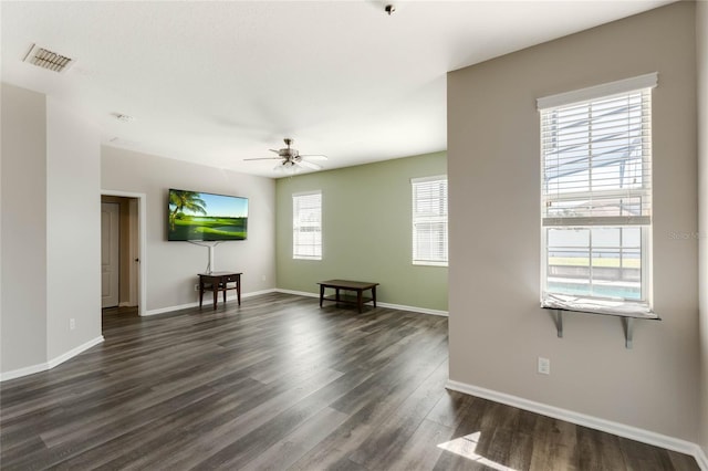 living room featuring visible vents, ceiling fan, baseboards, and dark wood finished floors