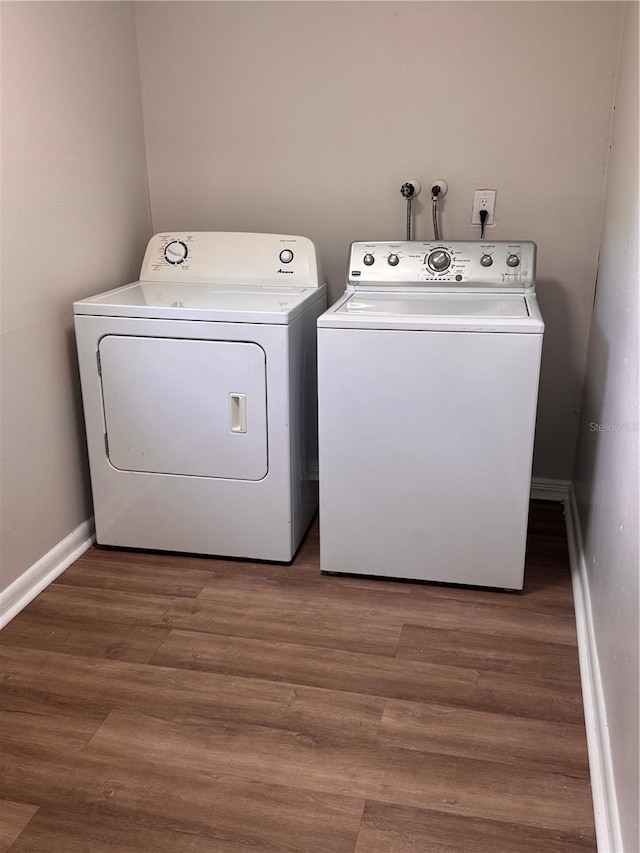 laundry area with baseboards, washer and dryer, laundry area, and wood finished floors
