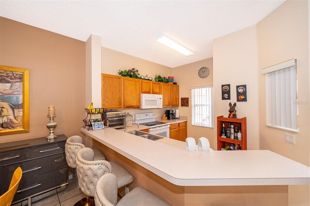 979 Park Terrace Cir, Kissimmee, FL 34746 - kitchen featuring light countertops, lofted ceiling, white appliances, a breakfast bar, and a sink