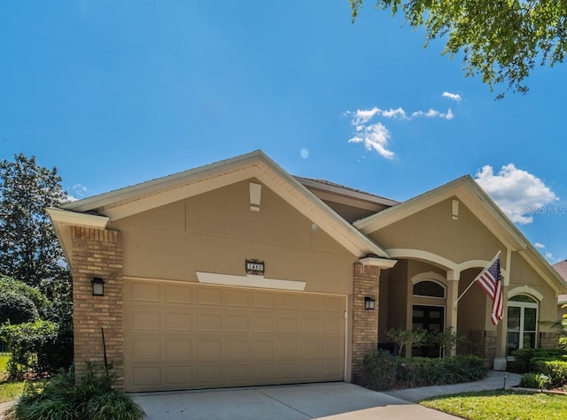 1450 Chessington Cir, Lake Mary, FL 32746 - view of front of house with brick siding, an attached garage, driveway, and stucco siding