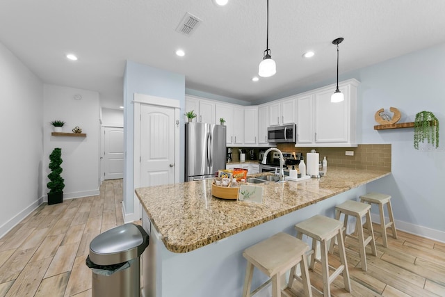 412 5th Ave S, Jacksonville Beach, FL 32250 - kitchen featuring white cabinetry, stainless steel appliances, decorative backsplash, a sink, and a peninsula