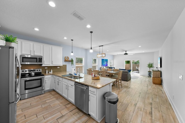 412 5th Ave S, Jacksonville Beach, FL 32250 - kitchen featuring a sink, a peninsula, open floor plan, stainless steel appliances, and white cabinets
