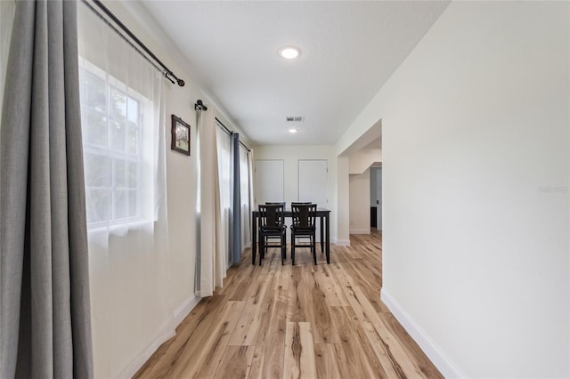 corridor featuring baseboards, light wood-style flooring, and visible vents