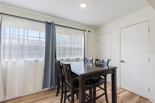 dining area with a textured ceiling and light wood-type flooring