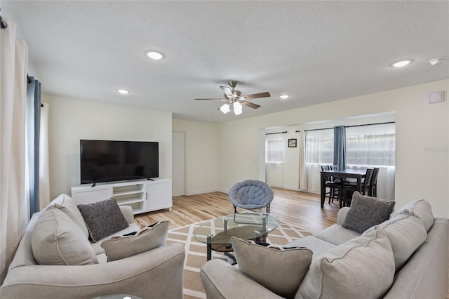living area with a textured ceiling, a ceiling fan, recessed lighting, and light wood-type flooring