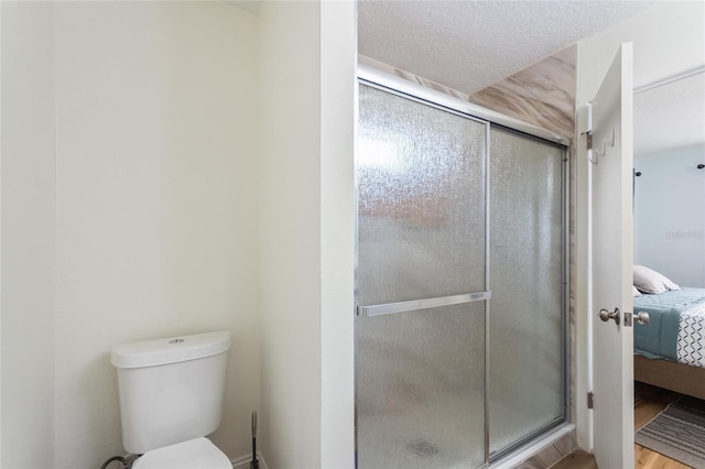 ensuite bathroom featuring a shower stall, toilet, ensuite bathroom, and a textured ceiling