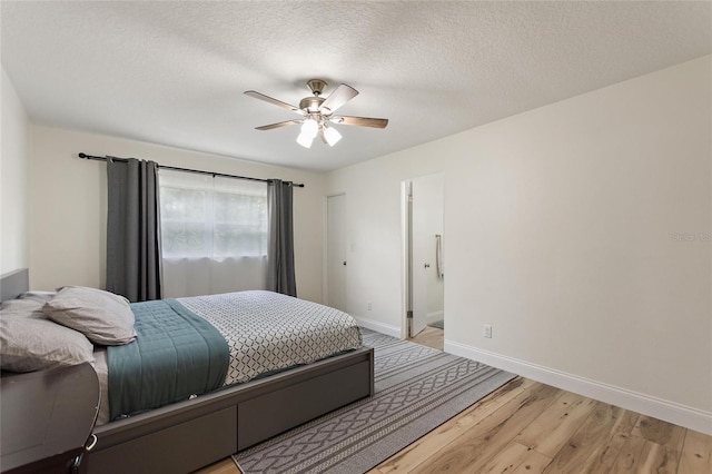 bedroom with baseboards, a textured ceiling, light wood-style flooring, and a ceiling fan
