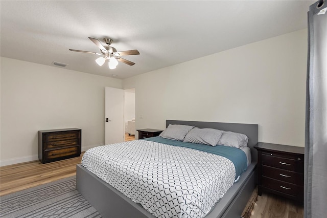 bedroom featuring baseboards, visible vents, wood finished floors, and ceiling fan