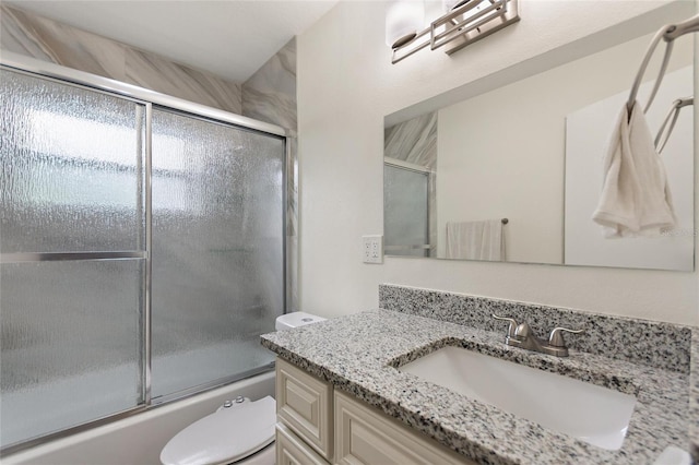 full bath with toilet, bath / shower combo with glass door, and vanity