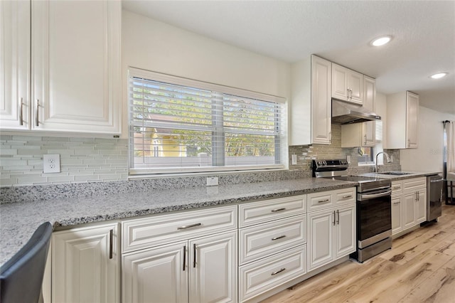 kitchen featuring white cabinets, light wood-style flooring, stainless steel appliances, under cabinet range hood, and a sink