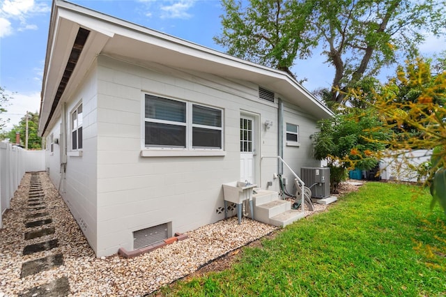view of front of home with fence, central AC, and a front lawn