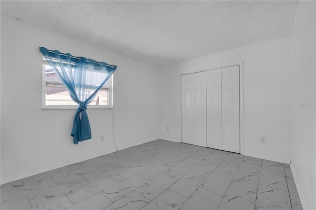 8720 Larwin Ln, Orlando, FL 32817 - unfurnished bedroom featuring baseboards, marble finish floor, a textured ceiling, and a closet
