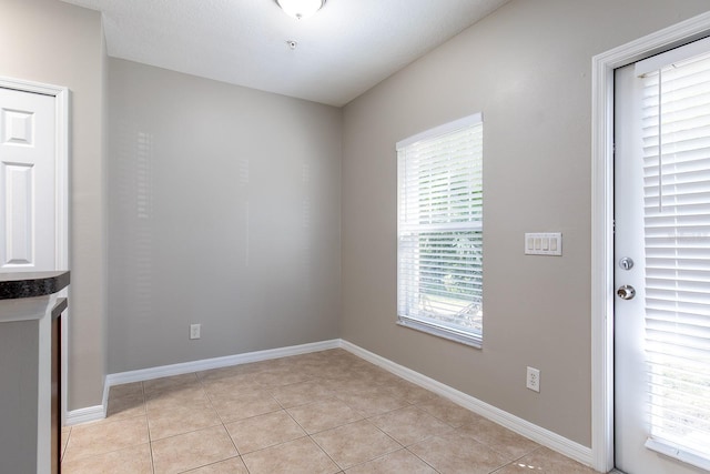 spare room with baseboards and light tile patterned floors