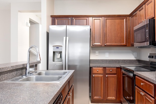 kitchen featuring a sink, dark countertops, appliances with stainless steel finishes, and brown cabinetry