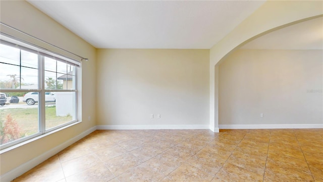 1402 Missouri Pl, Poinciana, FL 34759 - empty room with arched walkways, baseboards, and light tile patterned flooring