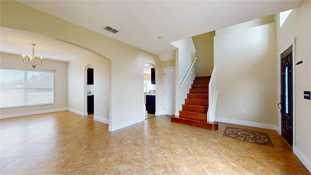 1402 Missouri Pl, Poinciana, FL 34759 - unfurnished living room with a chandelier, arched walkways, baseboards, stairs, and light tile patterned floors