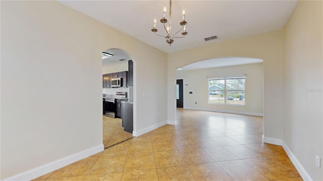 1402 Missouri Pl, Poinciana, FL 34759 - spare room with arched walkways, a chandelier, light tile patterned flooring, and baseboards