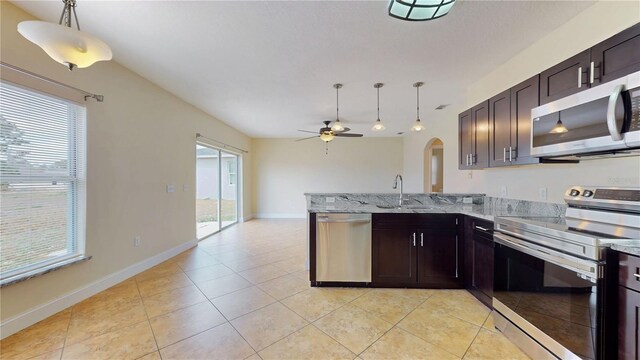 1402 Missouri Pl, Poinciana, FL 34759 - kitchen with stainless steel appliances, ceiling fan, arched walkways, light tile patterned floors, and a peninsula