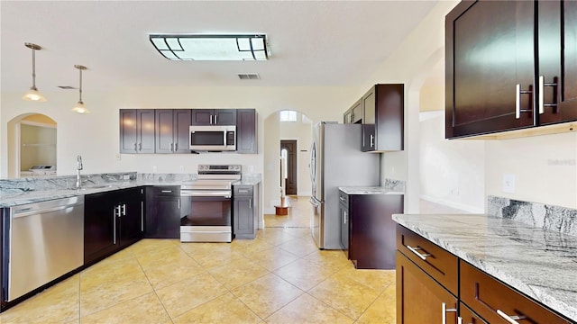 1402 Missouri Pl, Poinciana, FL 34759 - kitchen featuring stainless steel appliances, arched walkways, light stone counters, light tile patterned flooring, and pendant lighting