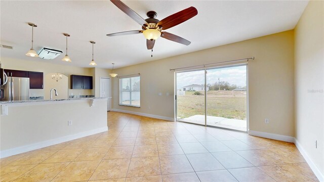 1402 Missouri Pl, Poinciana, FL 34759 - unfurnished living room featuring a sink, light tile patterned floors, a ceiling fan, and baseboards