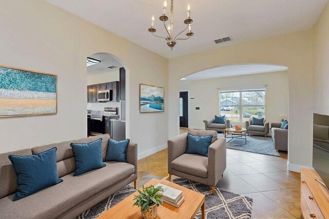 1402 Missouri Pl, Poinciana, FL 34759 - living room featuring arched walkways, light tile patterned flooring, a chandelier, and baseboards