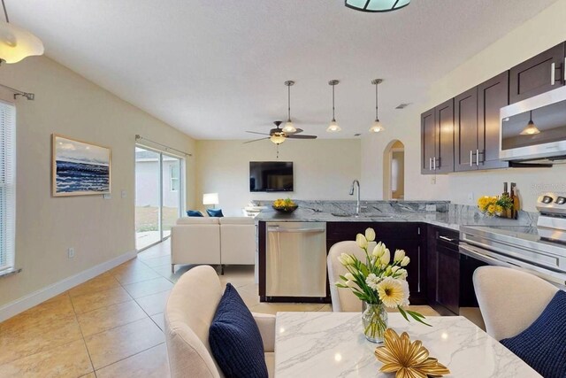 1402 Missouri Pl, Poinciana, FL 34759 - kitchen featuring appliances with stainless steel finishes, open floor plan, light tile patterned flooring, ceiling fan, and light stone countertops