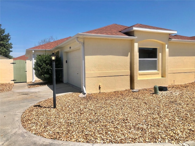 1324 Balboa Ct, The Villages, FL 32159 - view of front of house with a gate, a garage, stucco siding, roof with shingles, and driveway