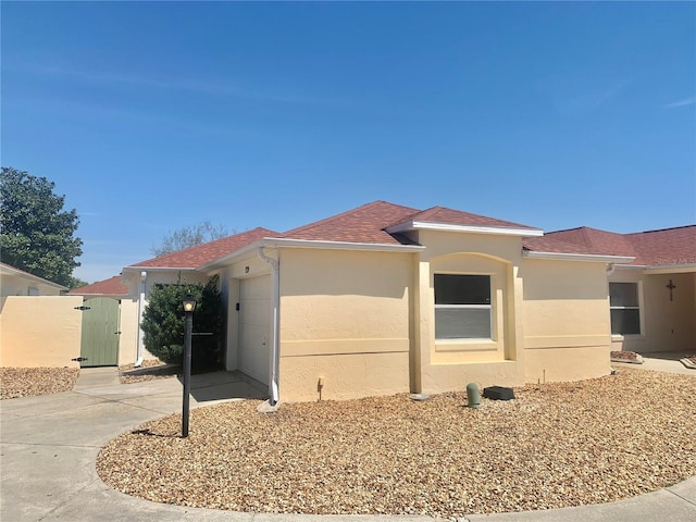 1324 Balboa Ct, The Villages, FL 32159 - view of front of property featuring stucco siding, a gate, a shingled roof, and an attached garage