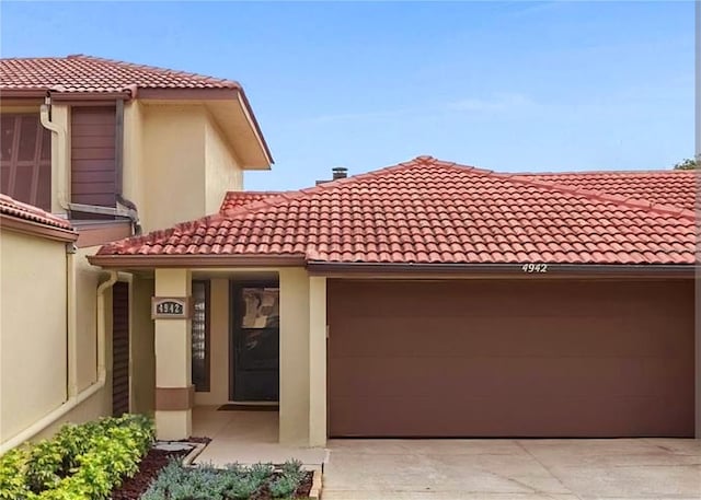 4942 Samoa Cir Unit 5, Orlando, FL 32808 - view of front of house with a tiled roof, concrete driveway, stucco siding, and an attached garage