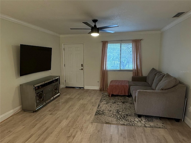 living room with ornamental molding, baseboards, light wood-style floors, visible vents, and ceiling fan