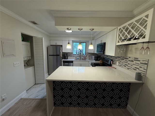 kitchen featuring white cabinets, visible vents, stacked washer / dryer, stainless steel appliances, and a sink