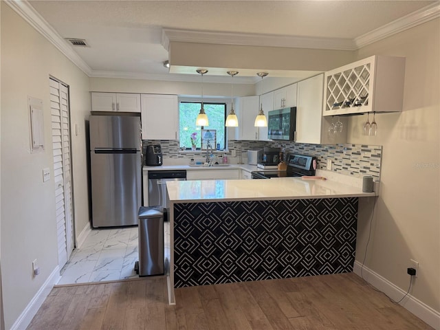 kitchen with visible vents, a peninsula, crown molding, appliances with stainless steel finishes, and a sink