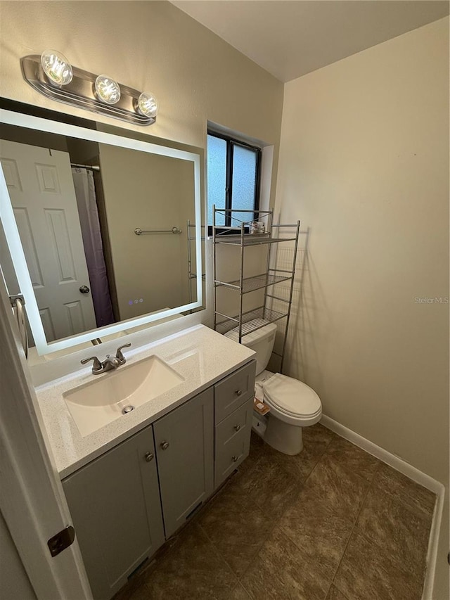 bathroom with baseboards, toilet, and vanity