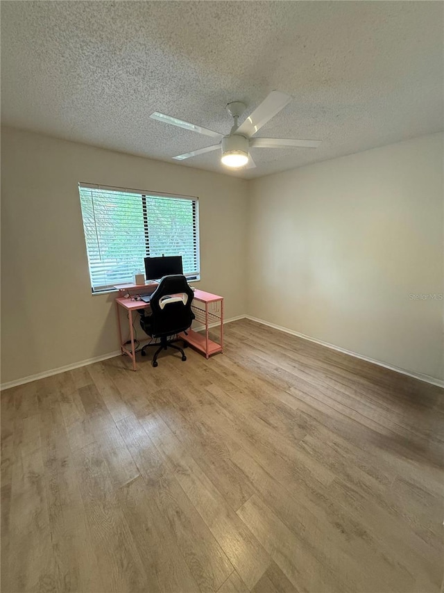 unfurnished office with a textured ceiling, baseboards, ceiling fan, and wood finished floors