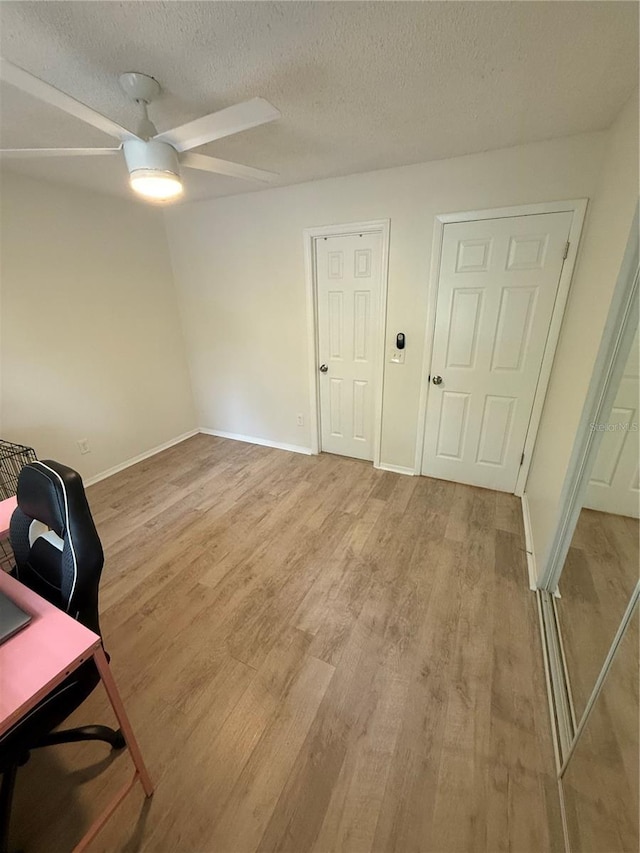 office space featuring a textured ceiling, ceiling fan, baseboards, and light wood finished floors
