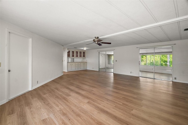 unfurnished living room with baseboards, visible vents, wood finished floors, and a ceiling fan